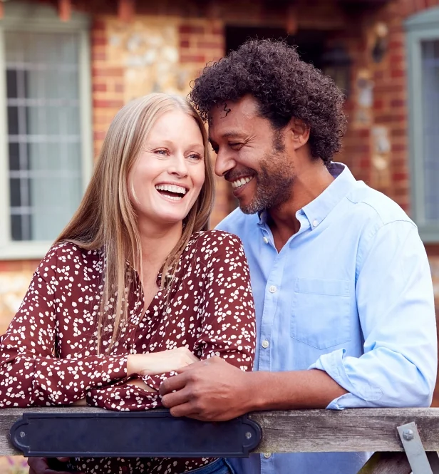 Man and woman affectionately holding eachother outside home