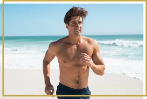 happy fit man running on beach after testosterone therapy